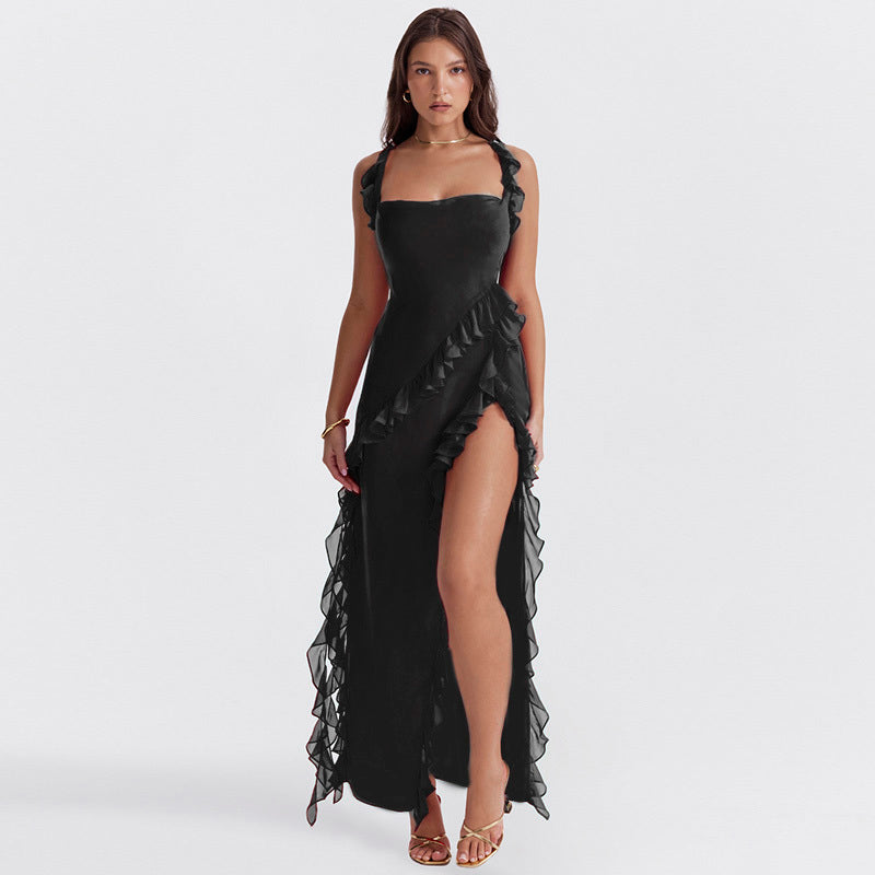 Abito lungo nero elegante con spacco alto e volant, indossato da modella. Perfetto per serate formali e occasioni speciali.
