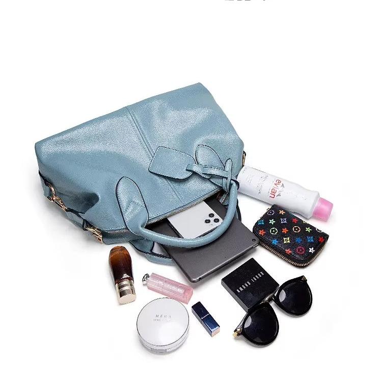 Borsa in pelle azzurra con accessori: occhiali da sole, rossetto, crema, smartphone, portafoglio colorato, profumo, e spray. Elegante e funzionale.