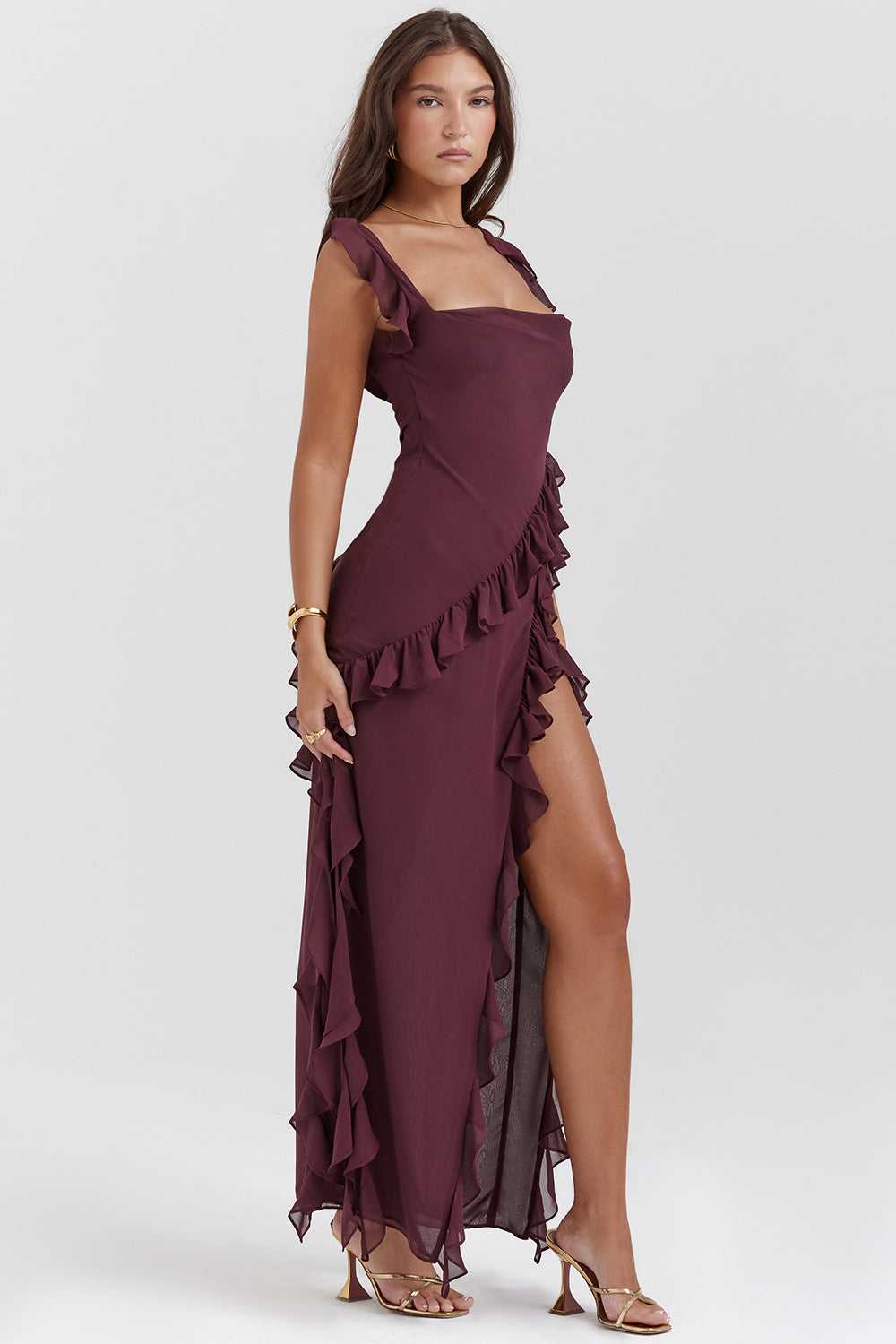 Abito lungo elegante bordeaux con volant, spacco laterale e spalline sottili. Perfetto per eventi serali e cerimonie. Moda donna sofisticata.