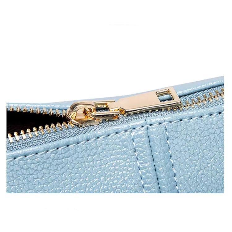 Chiusura lampo dorata su borsa in pelle blu chiaro, texture elegante. Accessorio moda donna, dettagli di lusso, design moderno.